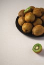 Kiwi fruits half sliced in black plate on vibrant plain white background Royalty Free Stock Photo