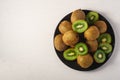 Kiwi fruits half sliced in black plate on vibrant plain white background Royalty Free Stock Photo