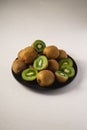 Kiwi fruits half sliced in black plate on vibrant plain white background Royalty Free Stock Photo