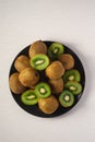 Kiwi fruits half sliced in black plate on vibrant plain white background Royalty Free Stock Photo