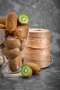 Kiwi fruits half sliced in glass bowl on dark black moody plain background, angle view