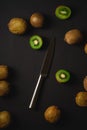 Kiwi fruits half sliced with kitchen knife on dark black moody plain background