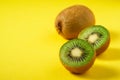 Kiwi fruits half sliced on vibrant plain yellow background