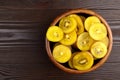 Kiwi Gold fruit slices in wooden bowl, top view. Sliced kiwi with yellow flesh in salad dish on brown background with copy space. Royalty Free Stock Photo