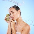 Kiwi, skincare and water splash of woman, beauty and wellness on studio blue background. Calm model, shower and healthy