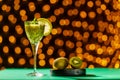 Kiwi smoothie garnished with mint in a glass against a background of blurry lights near fruits. Royalty Free Stock Photo