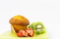 Kiwi and strawberry slices with corn muffin on green plate