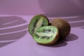 Kiwis sliced open on pink background with tropical leaf shadows