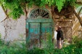 Kizilcahamam, Ankara/Turkey - June 07 2020: An old Turkish woman with a cane in her hand shows the antique door of a adobe brick