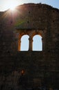 Bright sun rays appeared behind from the ruins of the wall with two windows of antique building.