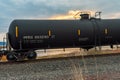 A black tank car of a freight train passing through Klamath Falls