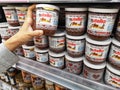 Klang, Malaysia - 26 November 2020 : Hand pick up a jar of Nutella Ferrero on the supermarket shelf.