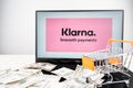 Klarna smooth payments logo on laptop with scattered dollar bills and shopping cart