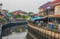 A klong or river channel with fishing boats, buildings and house fronts in Thailand