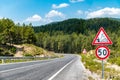 50 km h speed limit and warning signs on the winding asphalt road going through the forest on the mountain Royalty Free Stock Photo