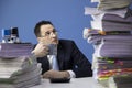 Knackered office employee looks frightened at high stack of documents Royalty Free Stock Photo