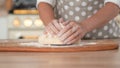 Knead dough, hand dough and flour close-up. A pastry chef in a grey polka-dot apron.
