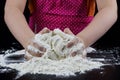 Kneading dough on a black table in a bakery. Baker& x27;s hands prepa Royalty Free Stock Photo