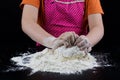 Kneading dough on a black table in a bakery. Baker& x27;s hands prepa Royalty Free Stock Photo
