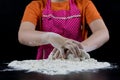 Kneading dough on a black table in a bakery. Baker& x27;s hands prepa Royalty Free Stock Photo
