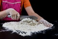 Kneading dough on a black table in a bakery. Baker& x27;s hands prepa Royalty Free Stock Photo