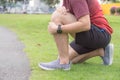 Knee Injuries. Young sport man holding knee with his hands in pain after suffering muscle injury during a running workout at park