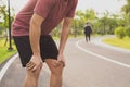 Knee Injuries. Young sport man holding knee with his hands in pain after suffering muscle injury during a running workout at park