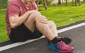 Knee Injuries. Young sport man holding knee with his hands in pain after suffering muscle injury during a running workout at park