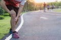 Knee Injuries. Young sport man holding knee with his hands in pain after suffering muscle injury during a running workout at park Royalty Free Stock Photo