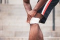 Knee injury concept, afro american guy bandaging his leg with a bandage, a man injured his knee in training