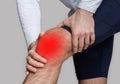 Knee injury or inflammation. Man in sportswear presses his hands to knee highlighted in red