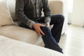 Knee pain arthritis body sick health care concept. Middle aged senior man suffering from knee ache sitting on sofa at Royalty Free Stock Photo