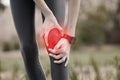 Knee pain, hands and injury in nature after accident, running or workout outdoors. Sports, health and woman athlete with Royalty Free Stock Photo