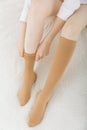 Knee socks or socks. Beige compression stockings on a woman in a white room. Girl putting on stockings at home Royalty Free Stock Photo