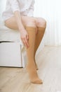 Knee socks or socks. Beige compression stockings on a woman in a white room. Girl putting on stockings at home Royalty Free Stock Photo