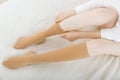 Knee socks or socks. Beige compression stockings on a woman in a white room. Girl putting on stockings at home Royalty Free Stock Photo