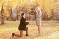 Kneeled man proposing ring to a woman in autumn Royalty Free Stock Photo