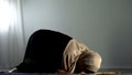 Kneeling arab woman prostrating on islamic praying rug, religious worship, faith