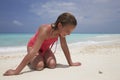 Kneeling girl looking at a tiny crab on a white sand beach Royalty Free Stock Photo