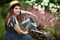 A young girl kneels down and waters the flowers in her garden with a watering can.