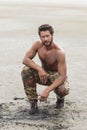 Kneeling Shirtless Soldier on the Beach Sand