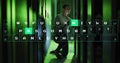 Kneeling tech testing server racks and data cables in green lit data center, with keyboard overlay Royalty Free Stock Photo