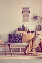 Knick knacks on wooden commode behind grey couch with pillows and blanket Royalty Free Stock Photo