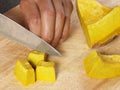 Knife cuts pumpkin on wooden chopping board