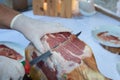 Knife cutting serrano man hand slicing of italian dry cured ham prosciutto Royalty Free Stock Photo