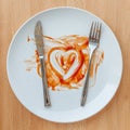 Knife and fork over in finish plate and heart shape ketchup.