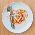 Knife and fork over in finish plate and heart shape ketchup.