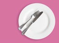 Knife and fork on white plate on pink background - top view photo Royalty Free Stock Photo