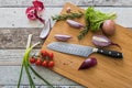 Knife with healthy food - vegetables, onion, salad, tomatoes, potato placed on a cutting board with wood background top view Royalty Free Stock Photo