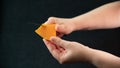A knife in her hand, she slices in an old piece of cheese, called mimolette, on a black background Royalty Free Stock Photo